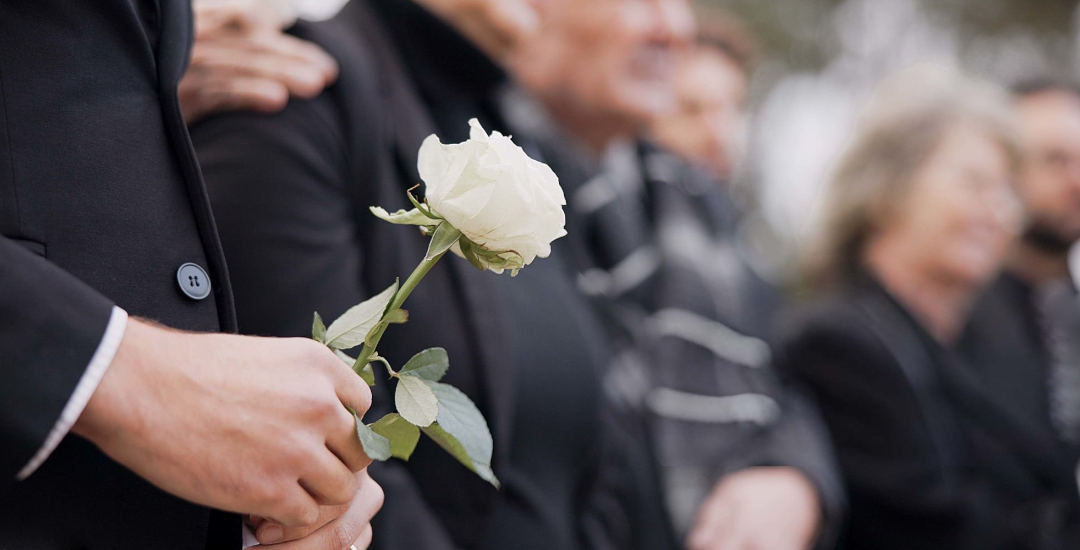 Personne tenant une rose blanche pendant la cérémonie d'adieu