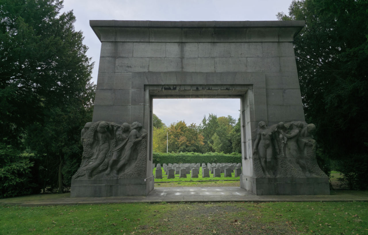 Monument de pierre du Cimetière de Bruxelles, avec les rangées de tombes alignées derrière l'arche.