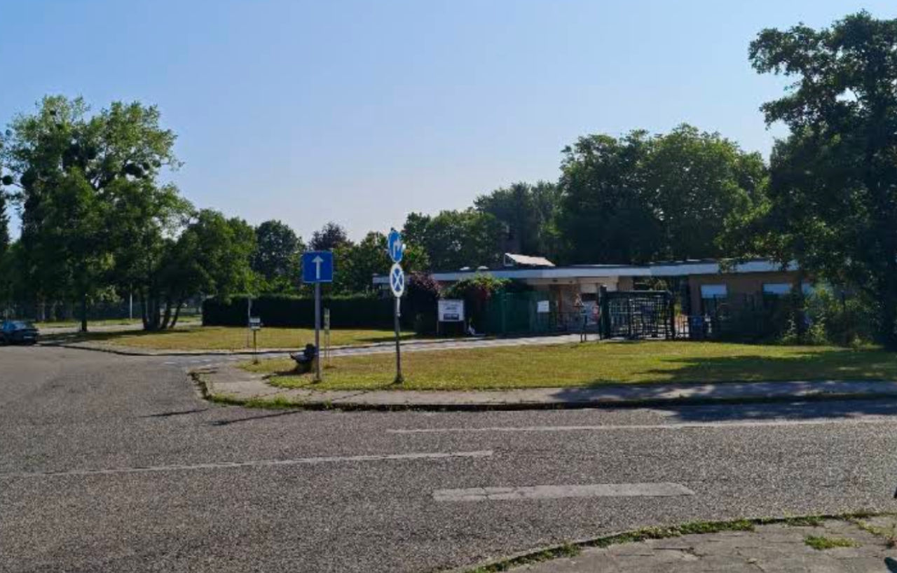 Entrée du Cimetière Multiconfessionnel de Bruxelles à Evere, avec le pavillon et la grille sur la pelouse.
