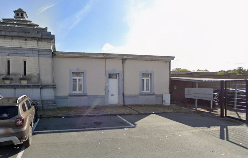 Crématorium d’Uccle, bâtiment en pierre claire surmonté d’un lanternon, avec son parking devant.