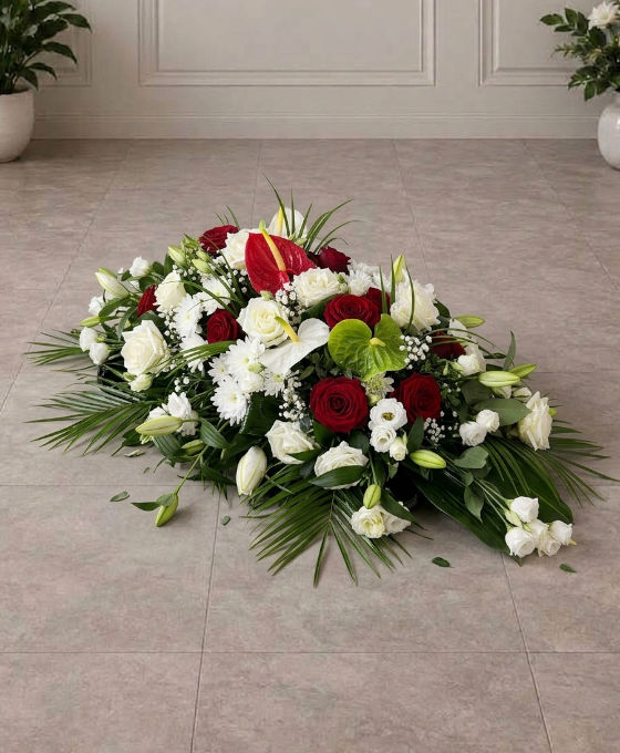 Pièce allongée en roses rouges et blanches, au sol Pièce allongée en roses rouges et blanches, avec anthuriums et lys, posée au sol dans une salle carrelée