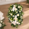 Pièce allongée en lys et roses blanches Bûche funéraire blanche et crème en lys et roses, avec des anthuriums blancs
