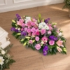 Pièce allongée en lys roses et lilas Bûche funéraire lys et roses en tons lilas, avec du statice violet
