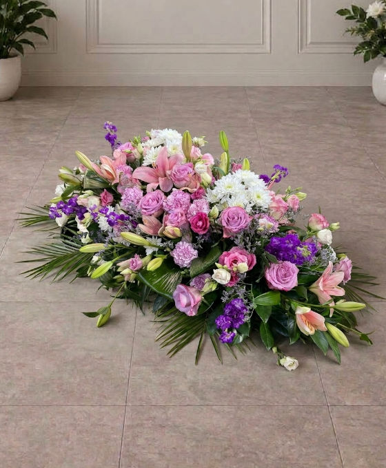 Pièce allongée en lys roses et lilas, au sol Pièce allongée en lys roses et lilas, avec roses et statice violet, posée au sol dans une salle carrelée