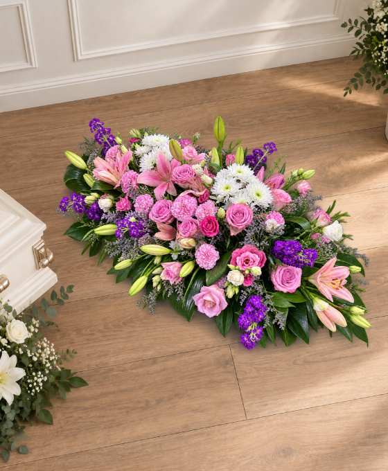 Bûche funéraire lys et roses en tons lilas, avec du statice violet