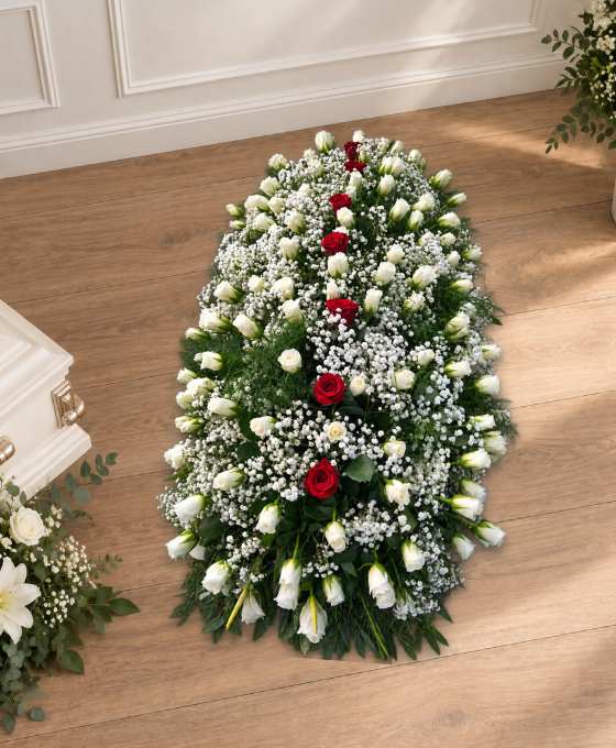 Grande pièce funéraire verticale en fleurs blanches, traversée d'une ligne de roses rouges