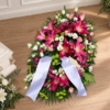 Pièce allongée en lys fuchsia et roses Bûche funéraire fuchsia en lys et roses, avec des chrysanthèmes verts et un ruban