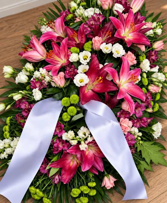 Gros plan : pièce allongée en lys fuchsia et roses Gros plan sur les fleurs : pièce allongée en lys fuchsia et roses, avec chrysanthèmes verts et ruban