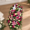 Pièce allongée en lys roses et roses fuchsia Bûche funéraire en dégradé de rose et fuchsia, en lys et roses avec un ruban
