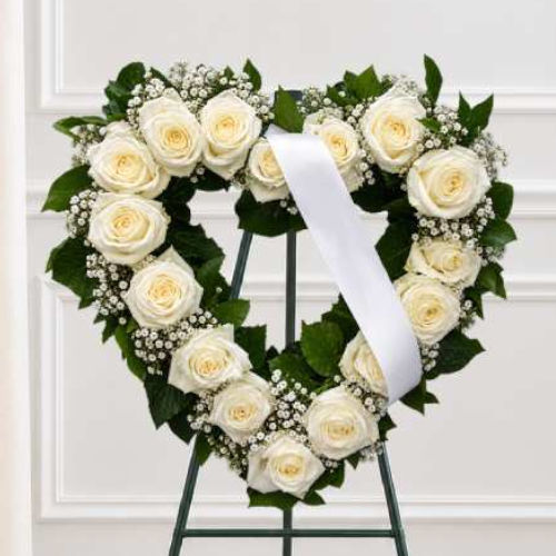 Cœur de fleurs deuil ouvert en roses crème, bordé de gypsophile avec ruban blanc, présenté sur pied