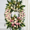 Couronne sur trépied en roses blanches Couronne de roses blanches sur trépied, avec des roses pâles, des lys et des anthuriums verts