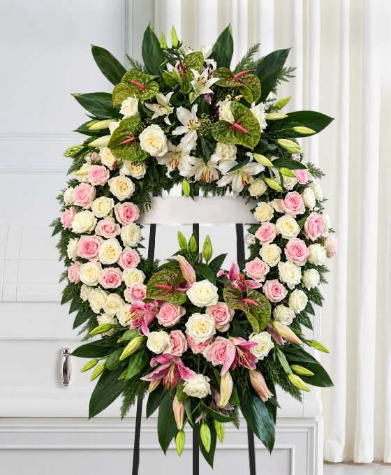 Couronne de roses blanches sur trépied, avec des roses pâles, des lys et des anthuriums verts