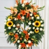 Couronne sur trépied en tournesols Couronne mortuaire tournesols, lys et glaïeuls orange, avec des roses blanches