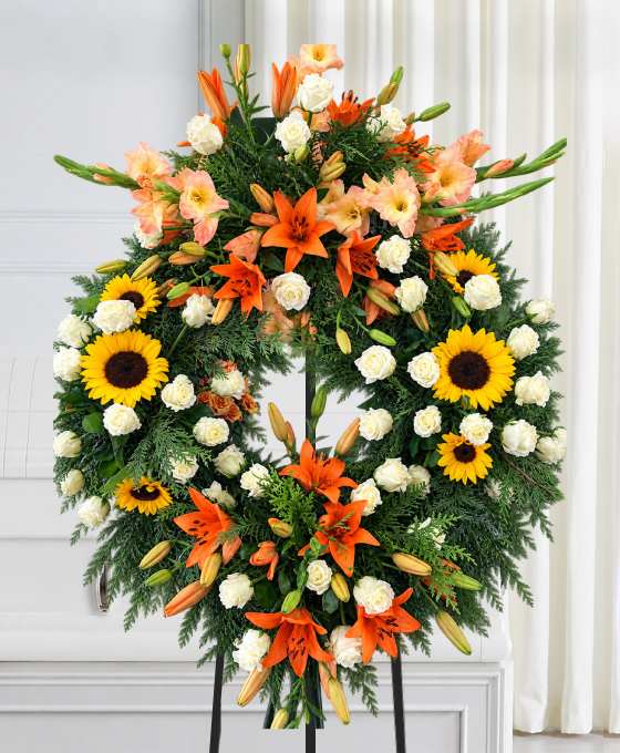 Couronne mortuaire tournesols, lys et glaïeuls orange, avec des roses blanches