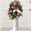 Coussin en lys et gerberas roses Coussin mortuaire rose en lys et gerberas, avec des roses et un large ruban blanc