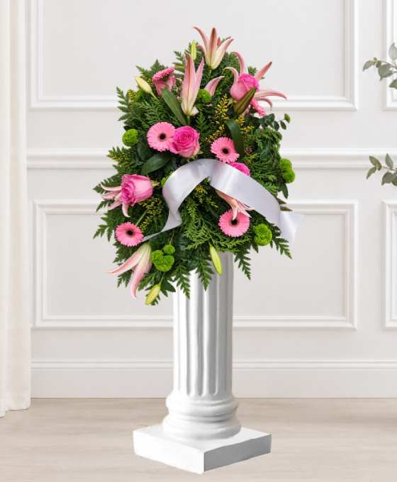 Coussin en lys et gerberas roses Coussin mortuaire rose en lys et gerberas, avec des roses et un large ruban blanc