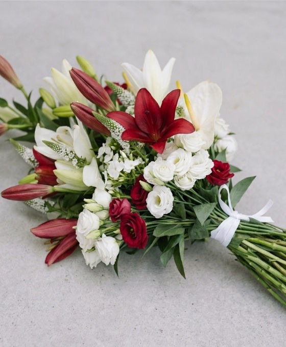 Gerbe en lys rouge et blanc avec roses Gerbe funéraire rouge et blanche en lys, roses et anthurium, liée par un ruban