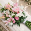 Gerbe rose posée sur le cercueil Gerbe funéraire rose en lys, lisianthus et véronique posée sur un cercueil clair